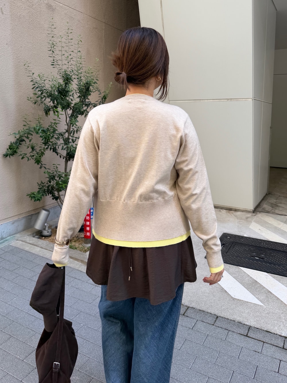 ベージュ系のカーディガン/ボレロ、ブラウン系のキャミソール、ブルー系のデニムパンツを着用したレディースの秋コーディネートの6枚目の写真