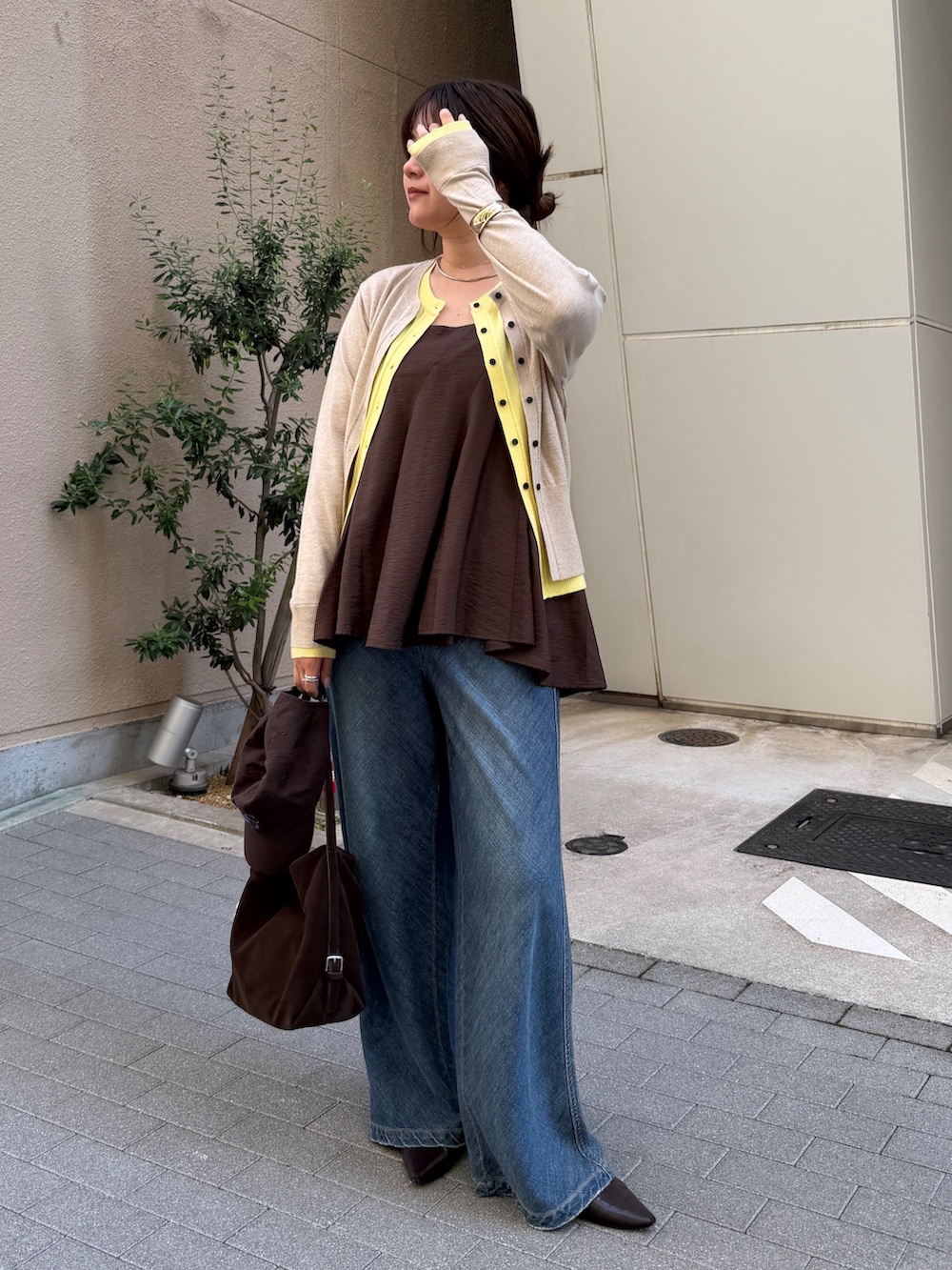 ベージュ系のカーディガン/ボレロ、ブラウン系のキャミソール、ブルー系のデニムパンツを着用したレディースの秋コーディネートの7枚目の写真