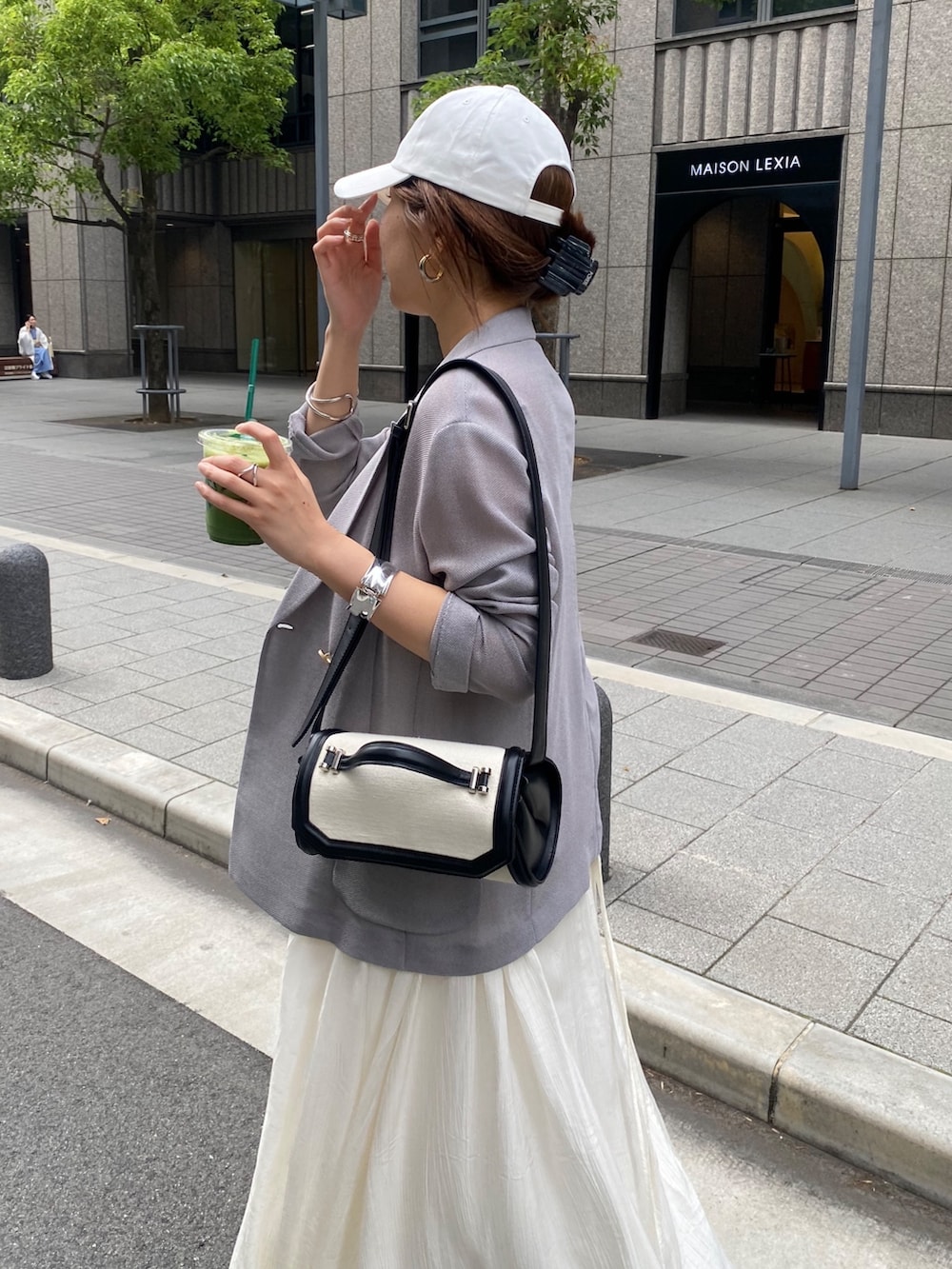 ブルー系のテーラードジャケット、ホワイト系のワンピース、ブラウン系のショルダーバッグを着用したレディースの春コーディネートの2枚目の写真