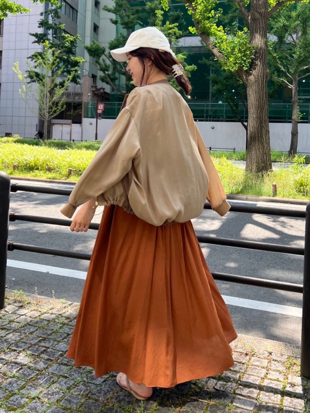 ベージュ系のブルゾン、ブラウン系のワンピース、ホワイト系のTシャツ/カットソーを着用したレディースの夏コーディネートの2枚目の写真