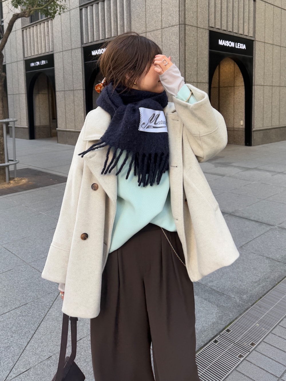 グリーン系のニット/セーター、ブラウン系のスラックス、グレー系のTシャツ/カットソーを着用したレディースの冬コーディネートの8枚目の写真