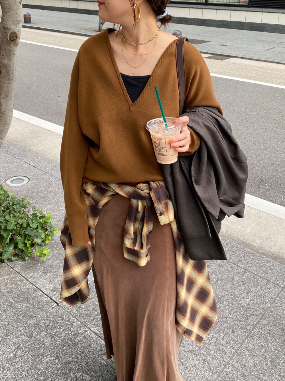 イエロー系のニット/セーター、ブラウン系のスカート、オレンジ系のシャツ/ブラウスを着用したレディースの冬コーディネートの3枚目の写真