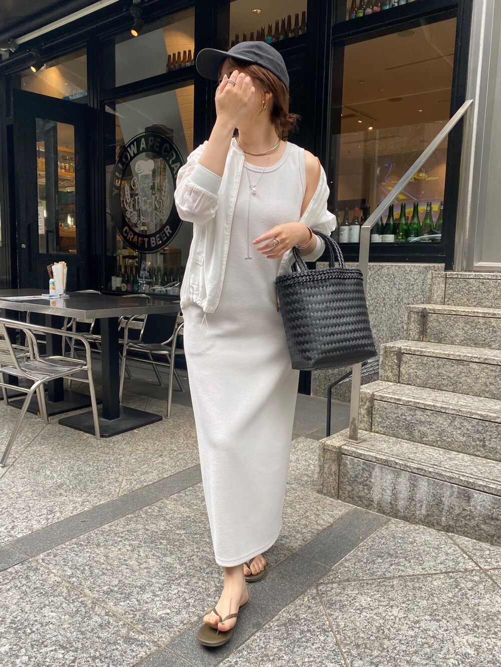 ベージュ系のワンピース、ホワイト系のブルゾン、ブラック系のかごバッグを着用したレディースの春コーディネートの3枚目の写真