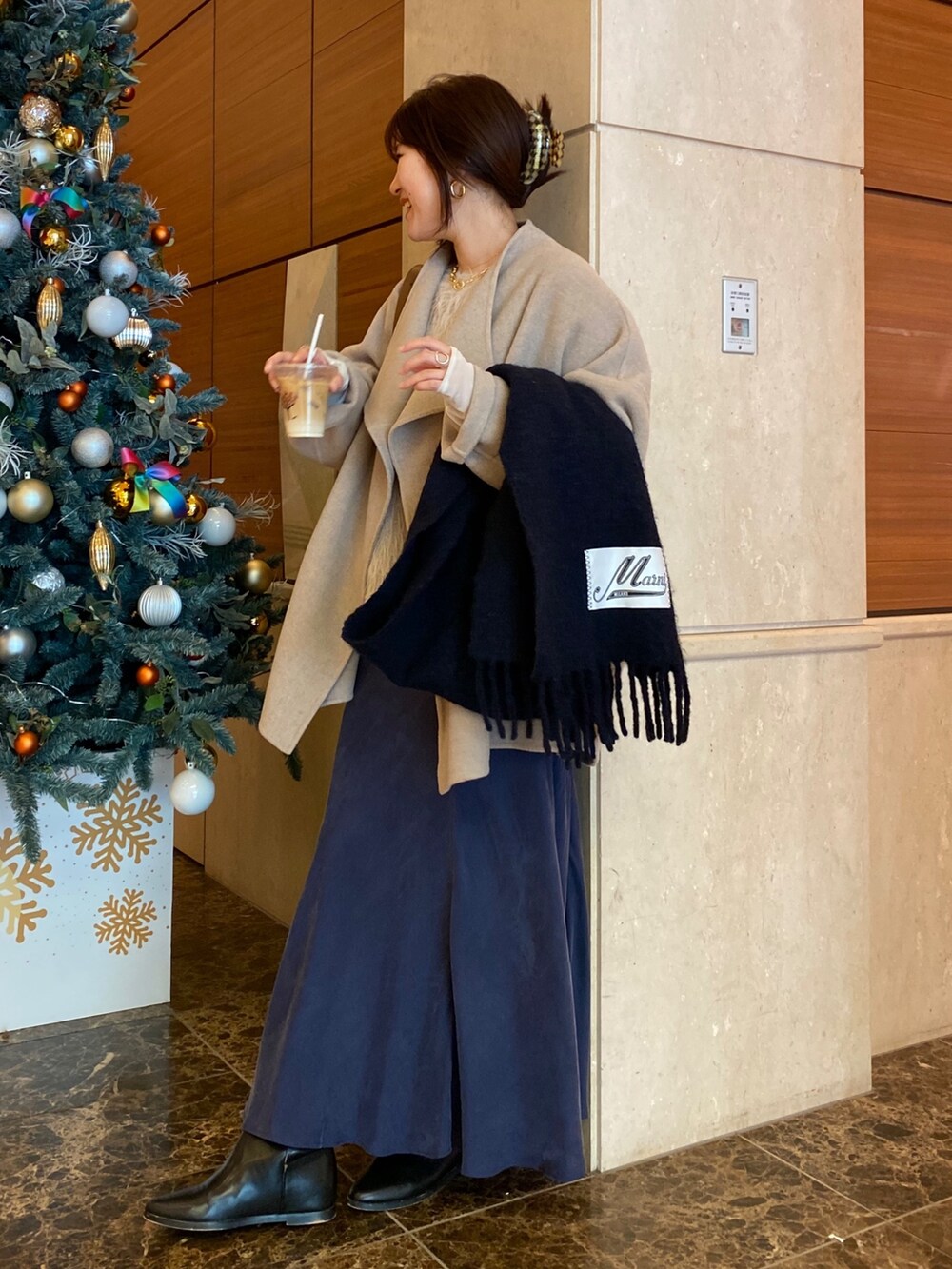 イエロー系のその他アウター、ホワイト系のニット/セーター、ホワイト系のスカートを着用したレディースの冬コーディネートの2枚目の写真