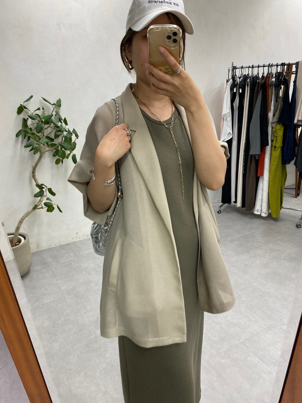 ベージュ系のテーラードジャケット、グリーン系のワンピース、シルバー系のショルダーバッグを着用したレディースの春コーディネートの3枚目の写真