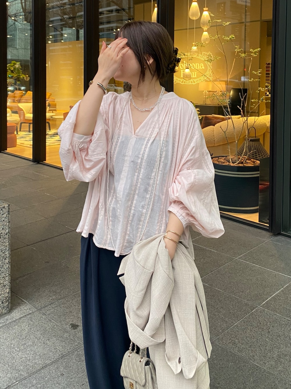 ピンク系のシャツ/ブラウス、ブルー系のスラックス、その他のネックレスを着用したレディースの春コーディネートの3枚目の写真