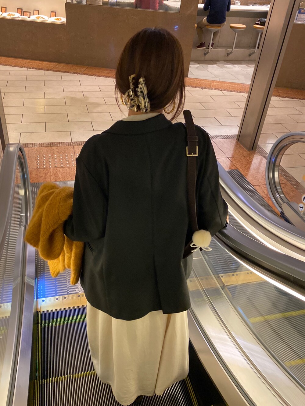 イエロー系のニット/セーター、ベージュ系のワンピース、ブラック系のテーラードジャケットを着用したレディースの冬コーディネートの5枚目の写真