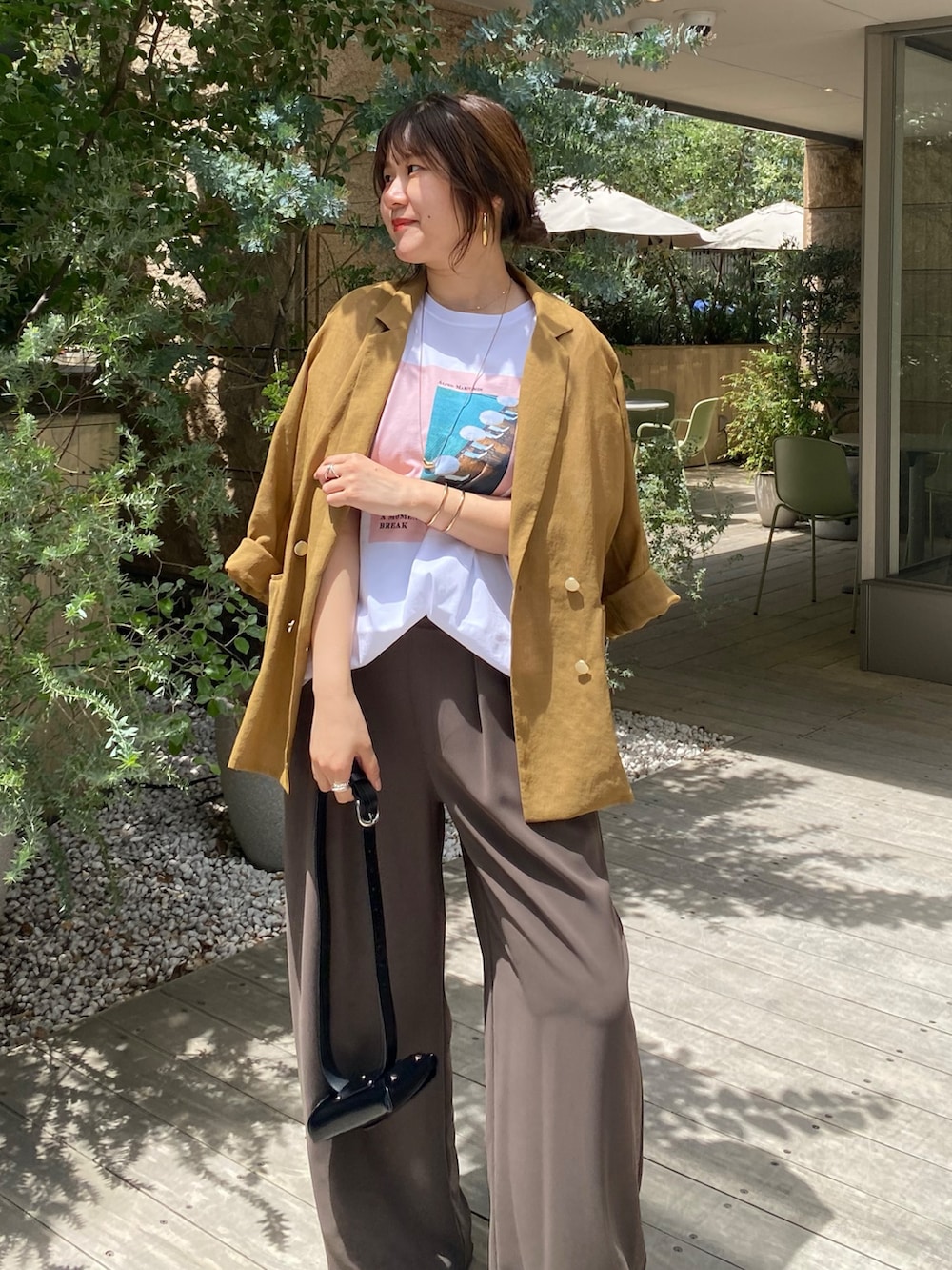 イエロー系のテーラードジャケット、ホワイト系のTシャツ/カットソー、ブラウン系のスラックスを着用したレディースの夏コーディネートの2枚目の写真