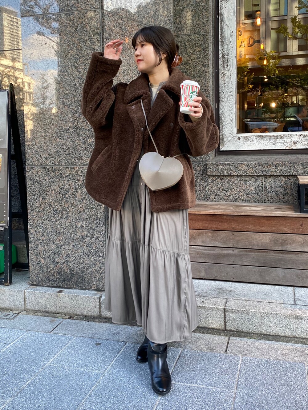 ブラウン系のその他アウター、ブラウン系のワンピース、ゴールド系のTシャツ/カットソーを着用したレディースの冬コーディネートの8枚目の写真