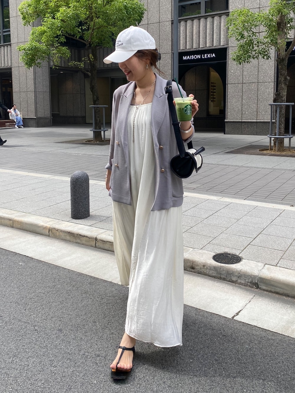 ブルー系のテーラードジャケット、ホワイト系のワンピース、ブラウン系のショルダーバッグを着用したレディースの春コーディネートの3枚目の写真