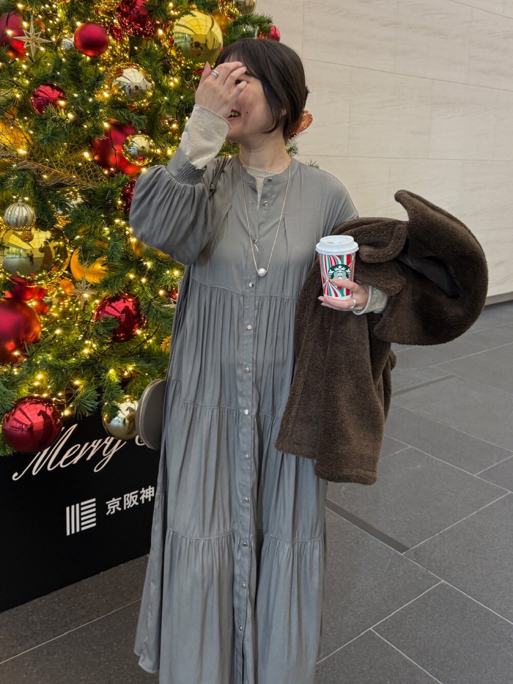 ブラウン系のその他アウター、ブラウン系のワンピース、ゴールド系のTシャツ/カットソーを着用したレディースの冬コーディネートの9枚目の写真