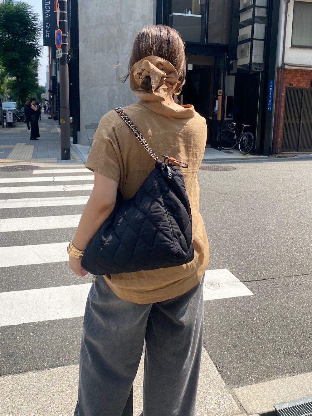 ベージュ系のシャツ/ブラウス、ブラック系のデニムパンツ、ブラウン系のシュシュを着用したレディースの夏コーディネートの5枚目の写真