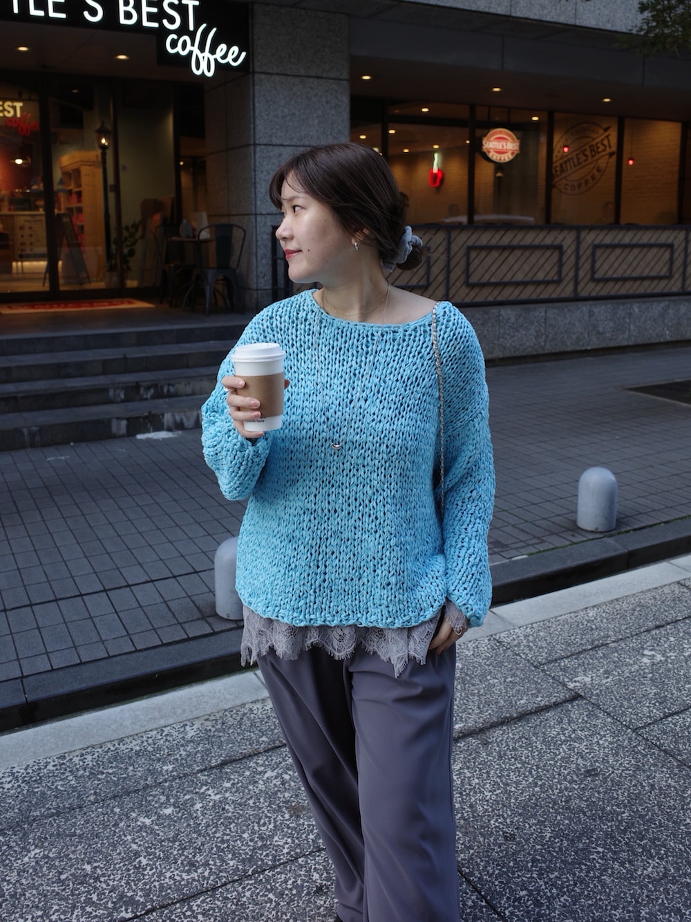 ブルー系のニット/セーター、グレー系のTシャツ/カットソー、グレー系のスラックスを着用したレディースの冬コーディネートの3枚目の写真