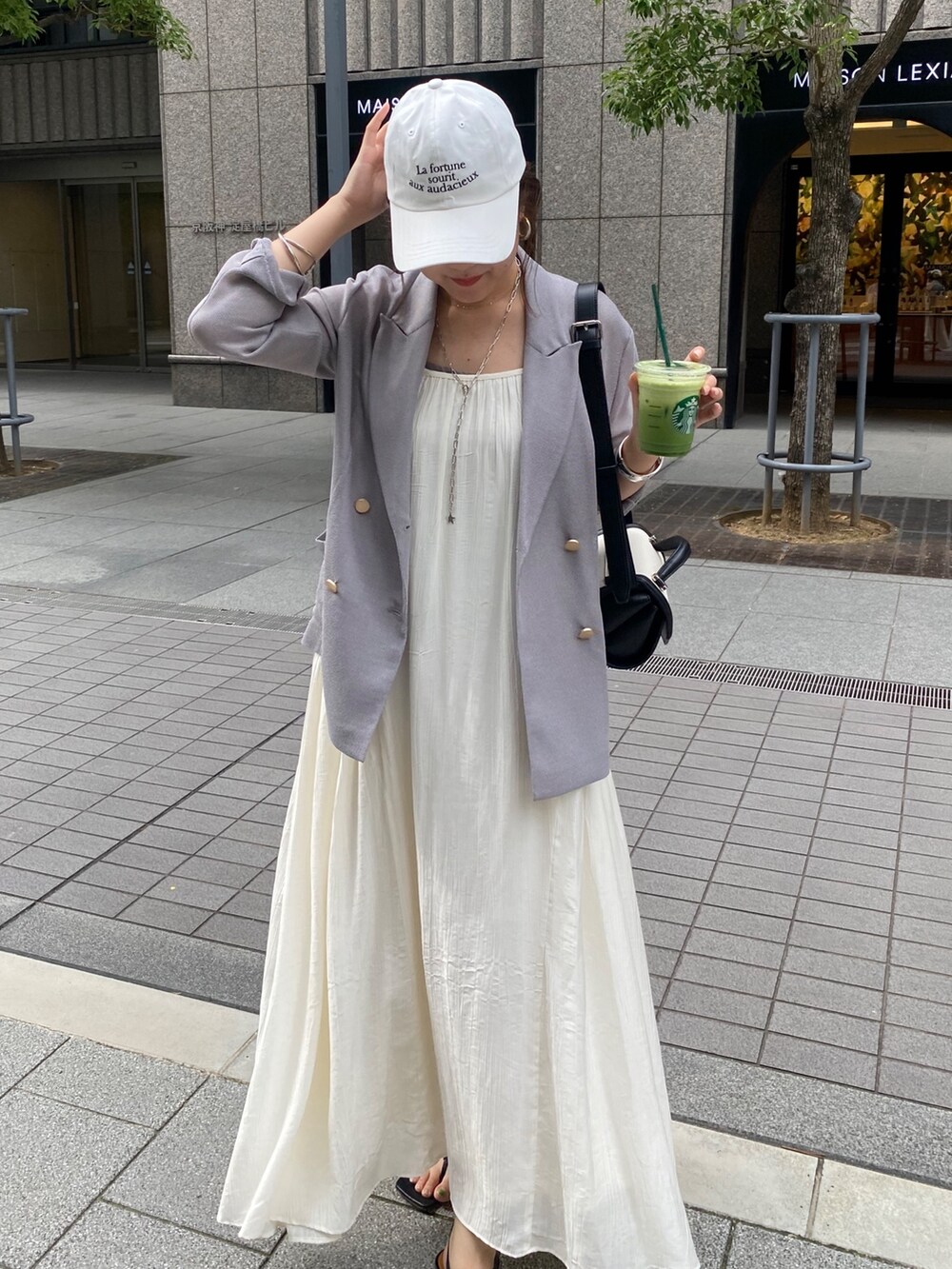 ブルー系のテーラードジャケット、ホワイト系のワンピース、ブラウン系のショルダーバッグを着用したレディースの春コーディネートの7枚目の写真