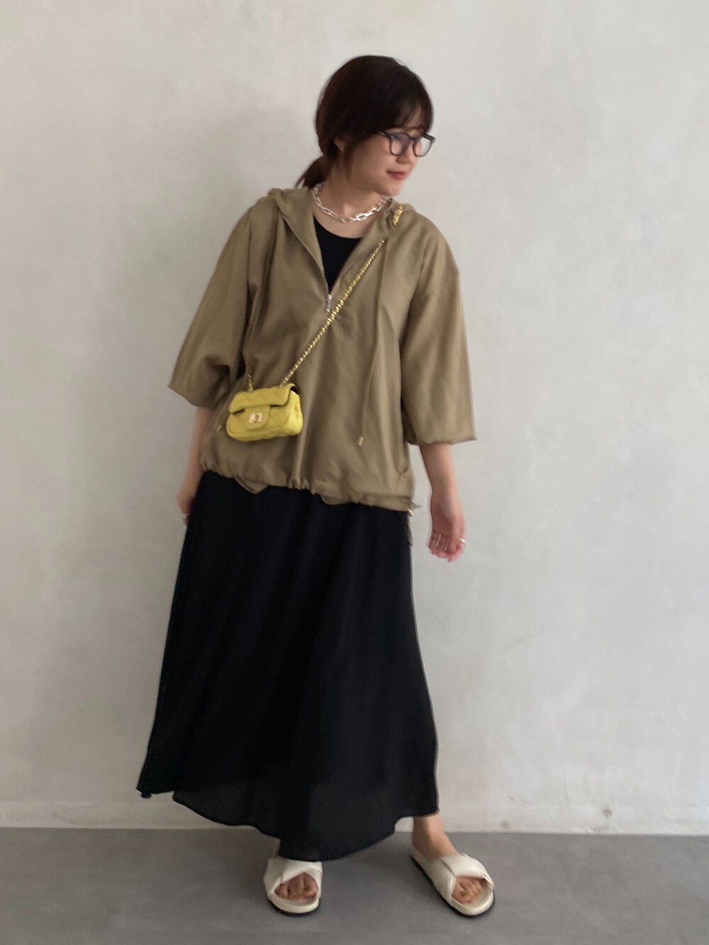 ベージュ系のシャツ/ブラウス、イエロー系のショルダーバッグ、ブラック系のワンピースを着用したレディースの夏コーディネートの2枚目の写真