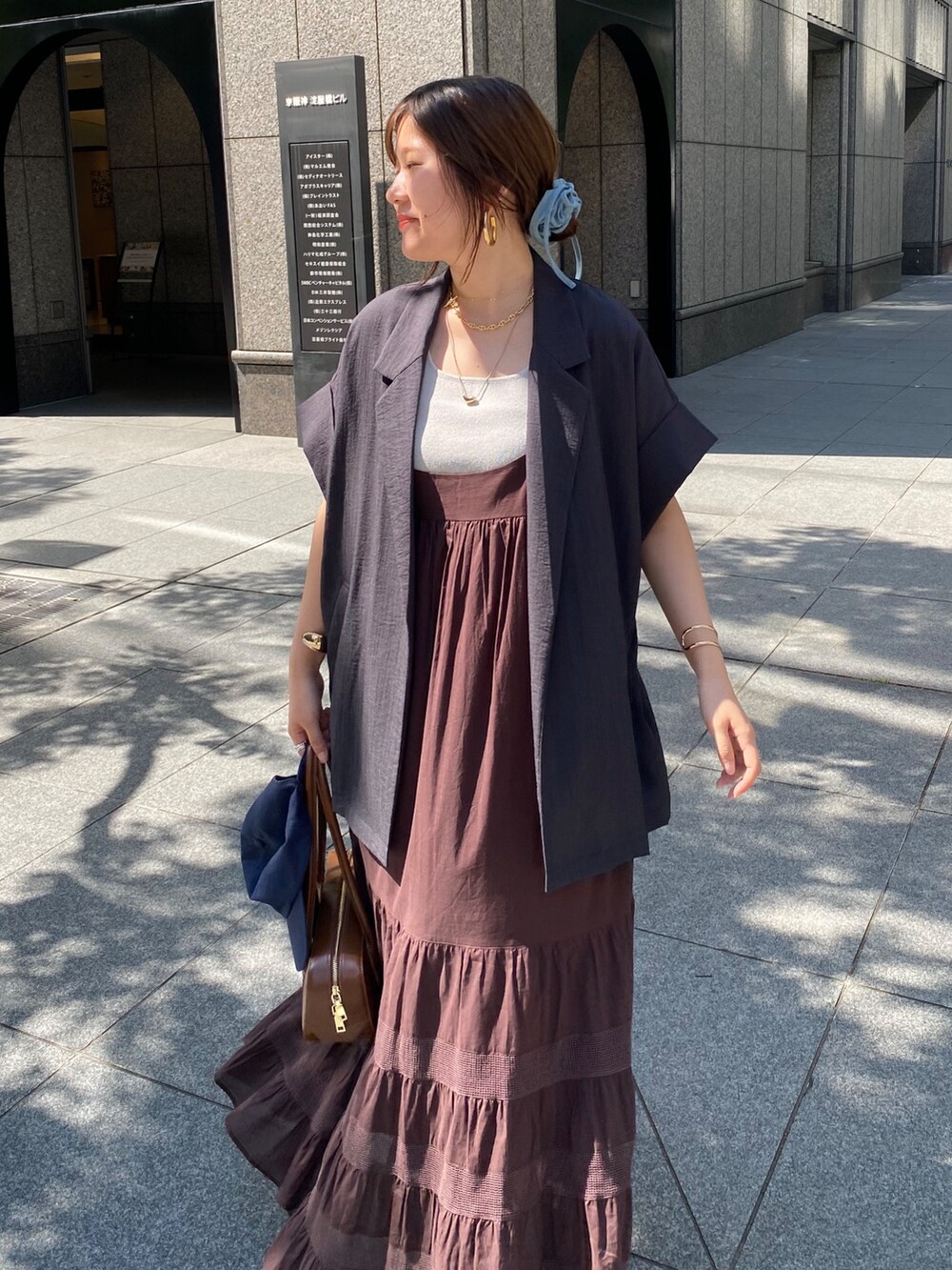 グレー系のテーラードジャケット、ブラウン系のワンピース、ブルー系のキャップを着用したレディースの夏コーディネートの3枚目の写真