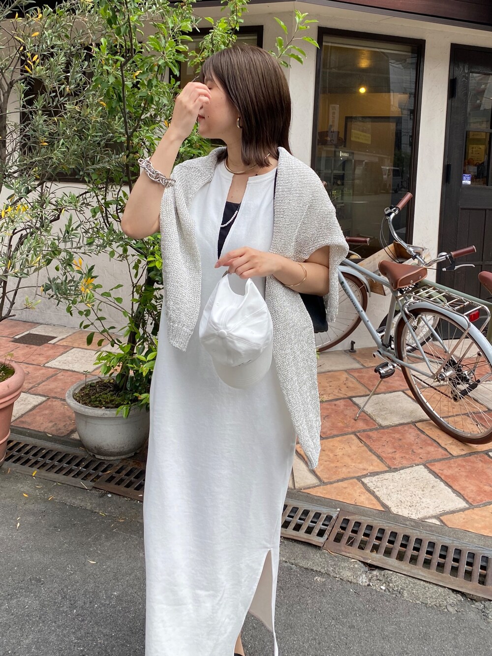 ホワイト系のワンピース、ホワイト系のキャップ、ホワイト系のネックレスを着用したレディースの夏コーディネートの2枚目の写真