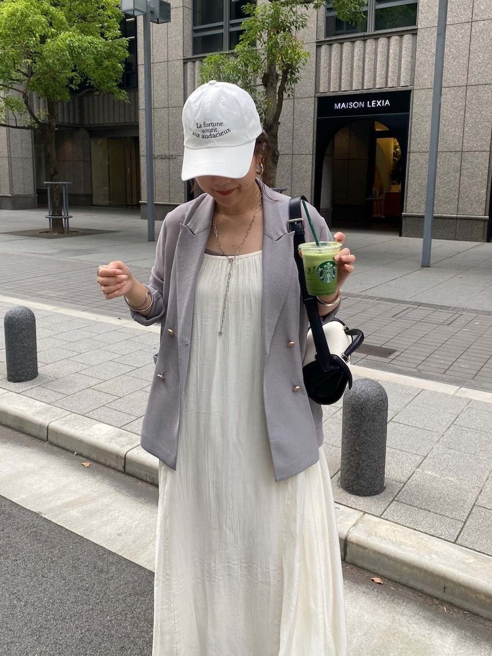 ブルー系のテーラードジャケット、ホワイト系のワンピース、ブラウン系のショルダーバッグを着用したレディースの春コーディネートの4枚目の写真