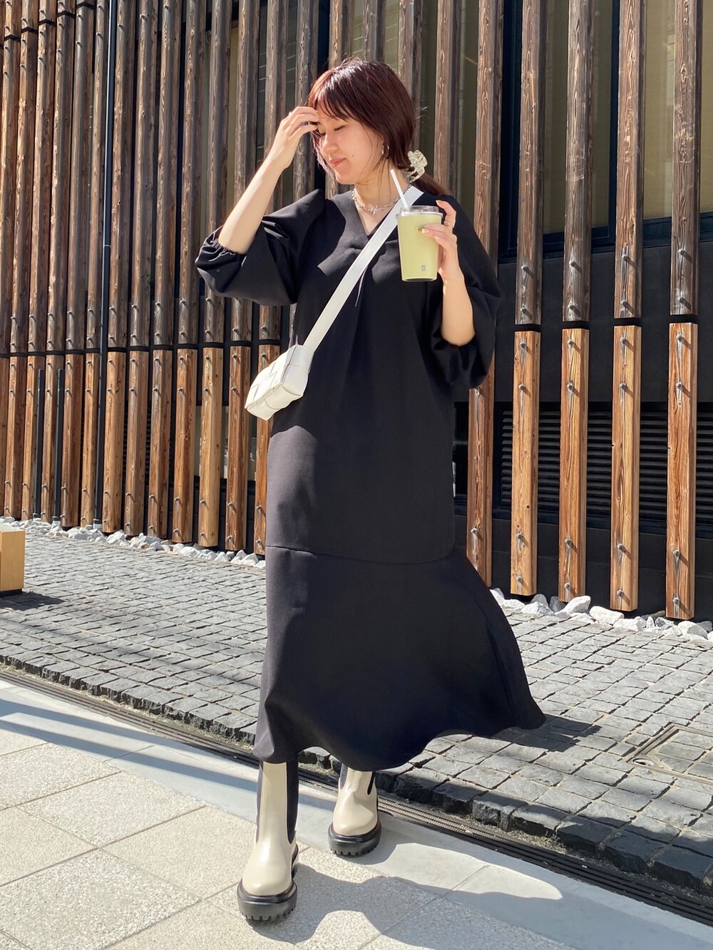 ブラック系のワンピース、ホワイト系のショルダーバッグ、ホワイト系のブーツを着用したレディースの夏コーディネートの3枚目の写真