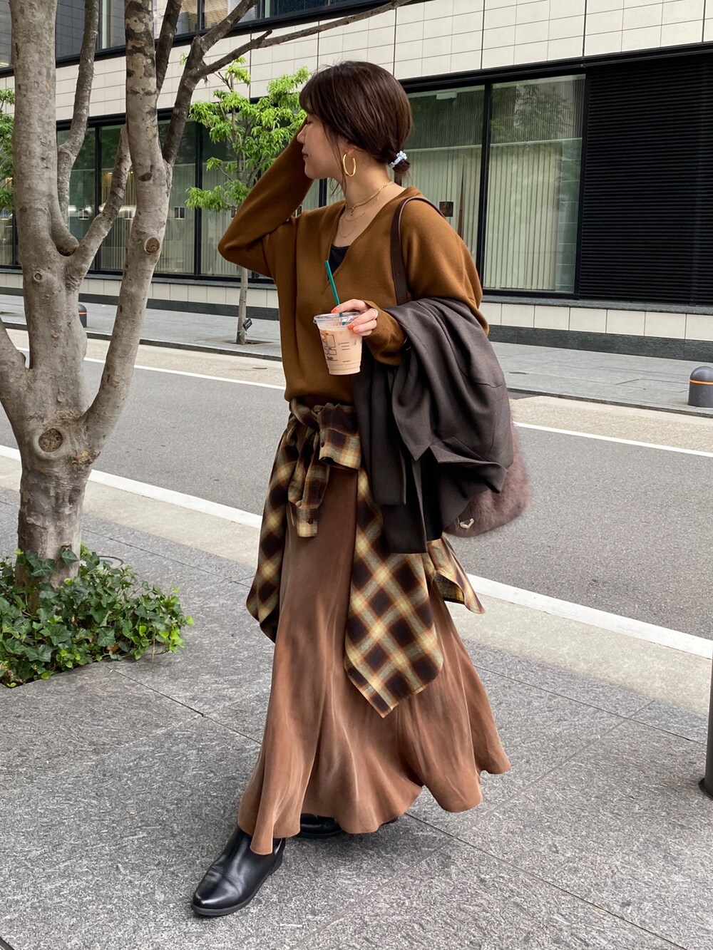 イエロー系のニット/セーター、ブラウン系のスカート、オレンジ系のシャツ/ブラウスを着用したレディースの冬コーディネートの9枚目の写真