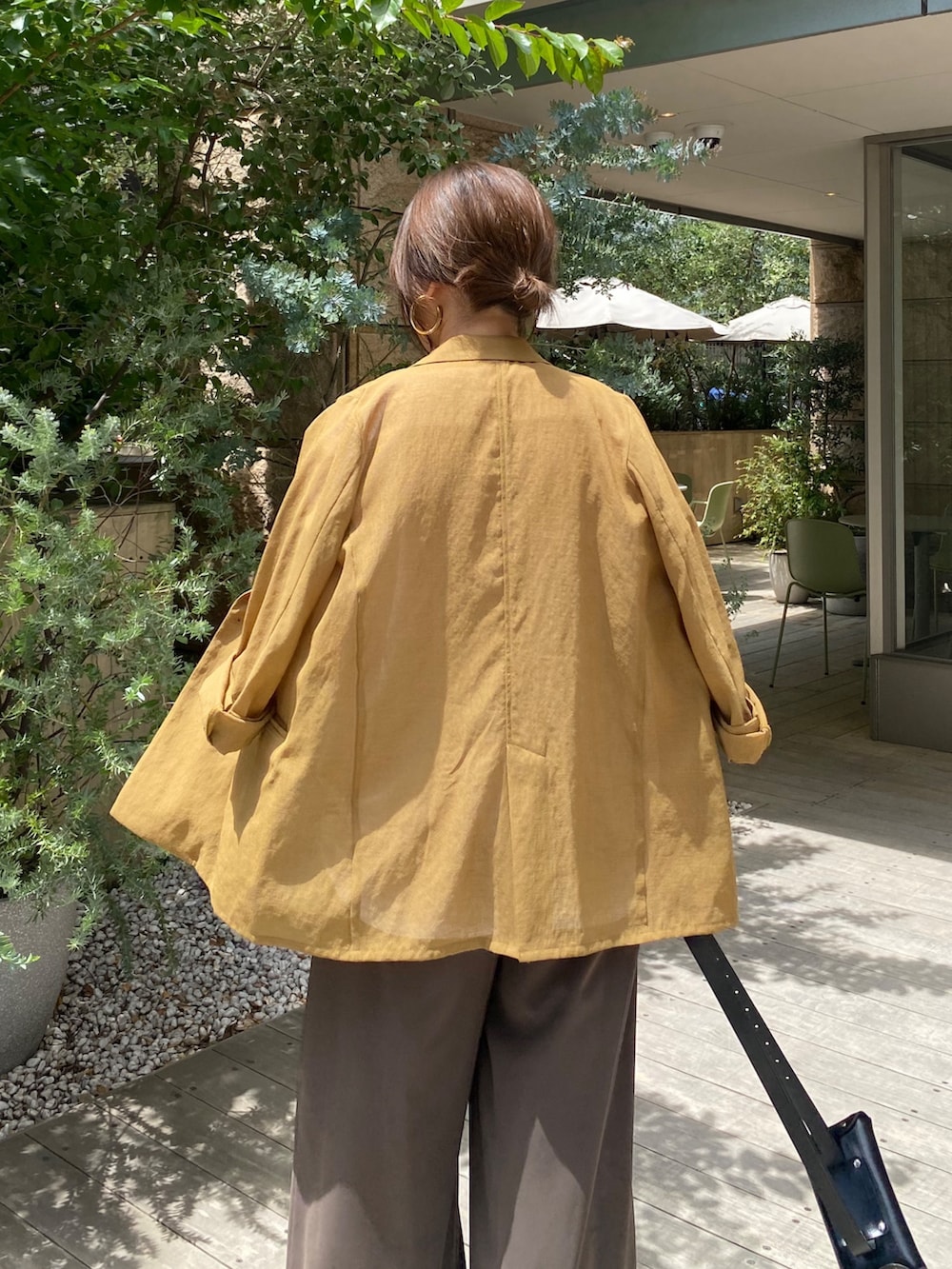 イエロー系のテーラードジャケット、ホワイト系のTシャツ/カットソー、ブラウン系のスラックスを着用したレディースの夏コーディネートの5枚目の写真