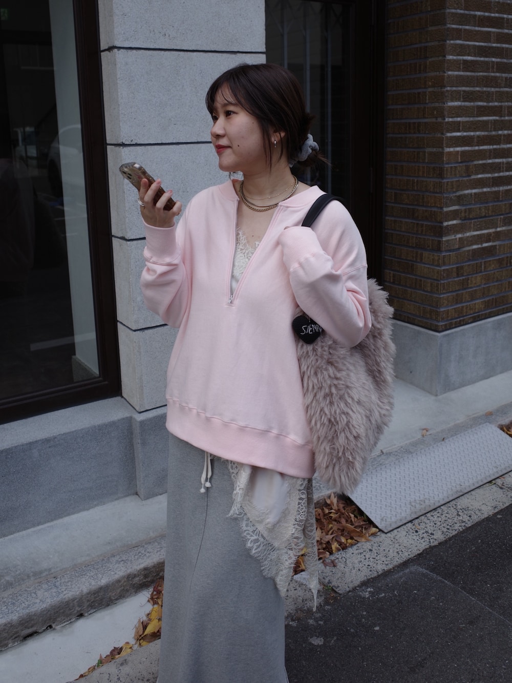 ピンク系のスウェット、ベージュ系のキャミソール、グレー系のスカートを着用したレディースの冬コーディネートの5枚目の写真