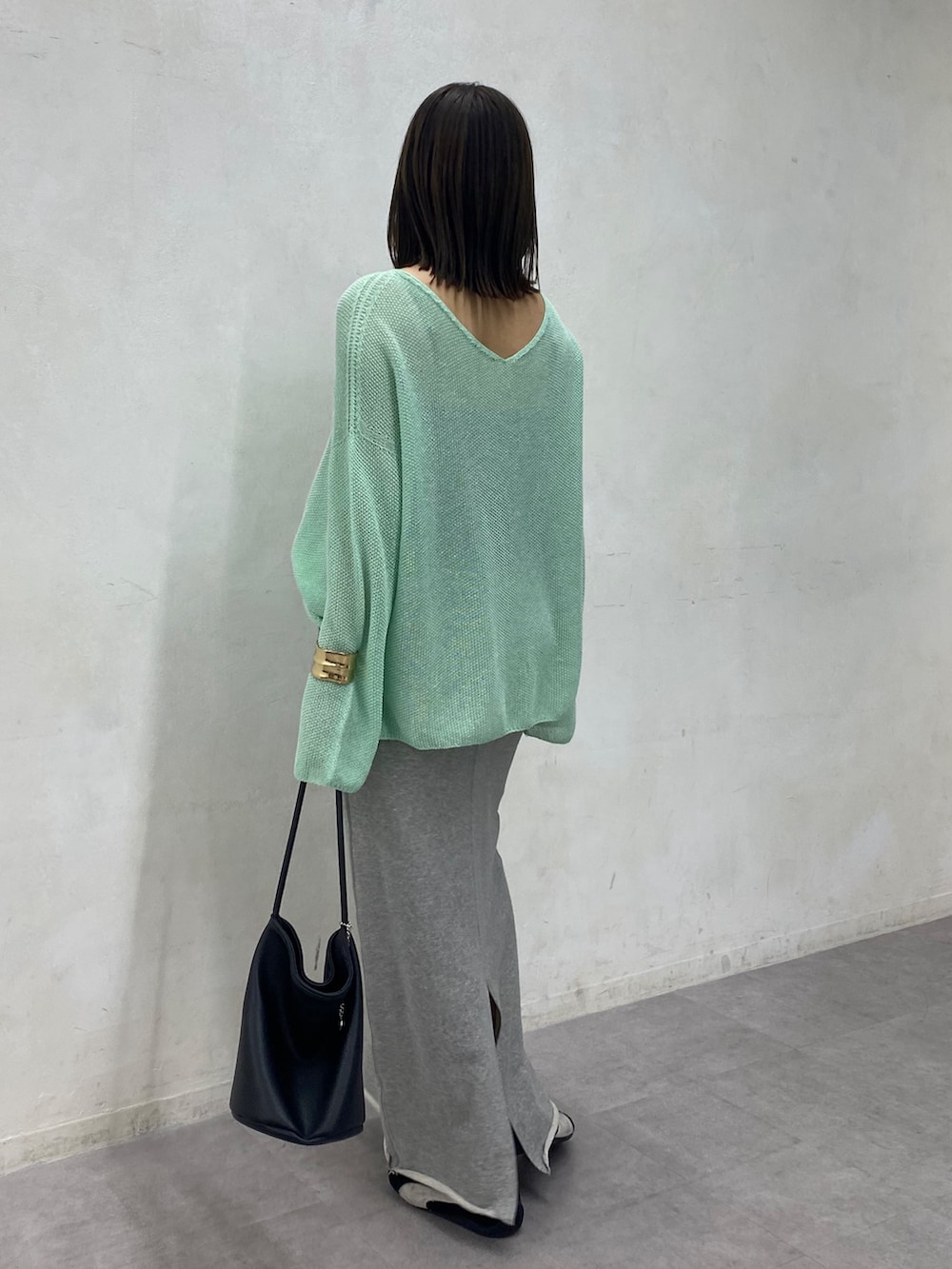 グリーン系のニット/セーター、グレー系のスカートを着用したレディースの春コーディネートの4枚目の写真