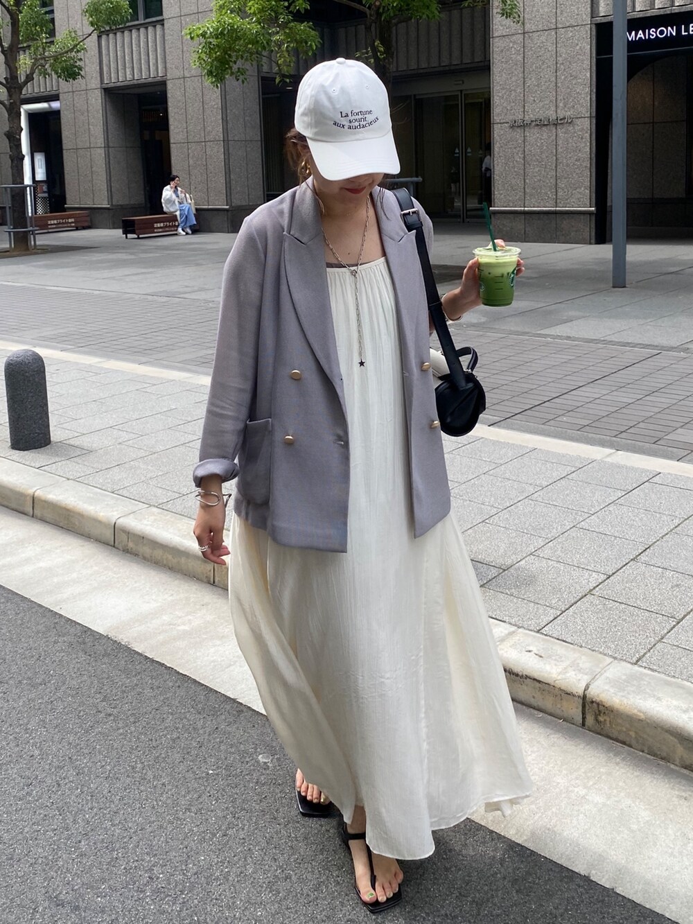 ブルー系のテーラードジャケット、ホワイト系のワンピース、ブラウン系のショルダーバッグを着用したレディースの春コーディネートの6枚目の写真