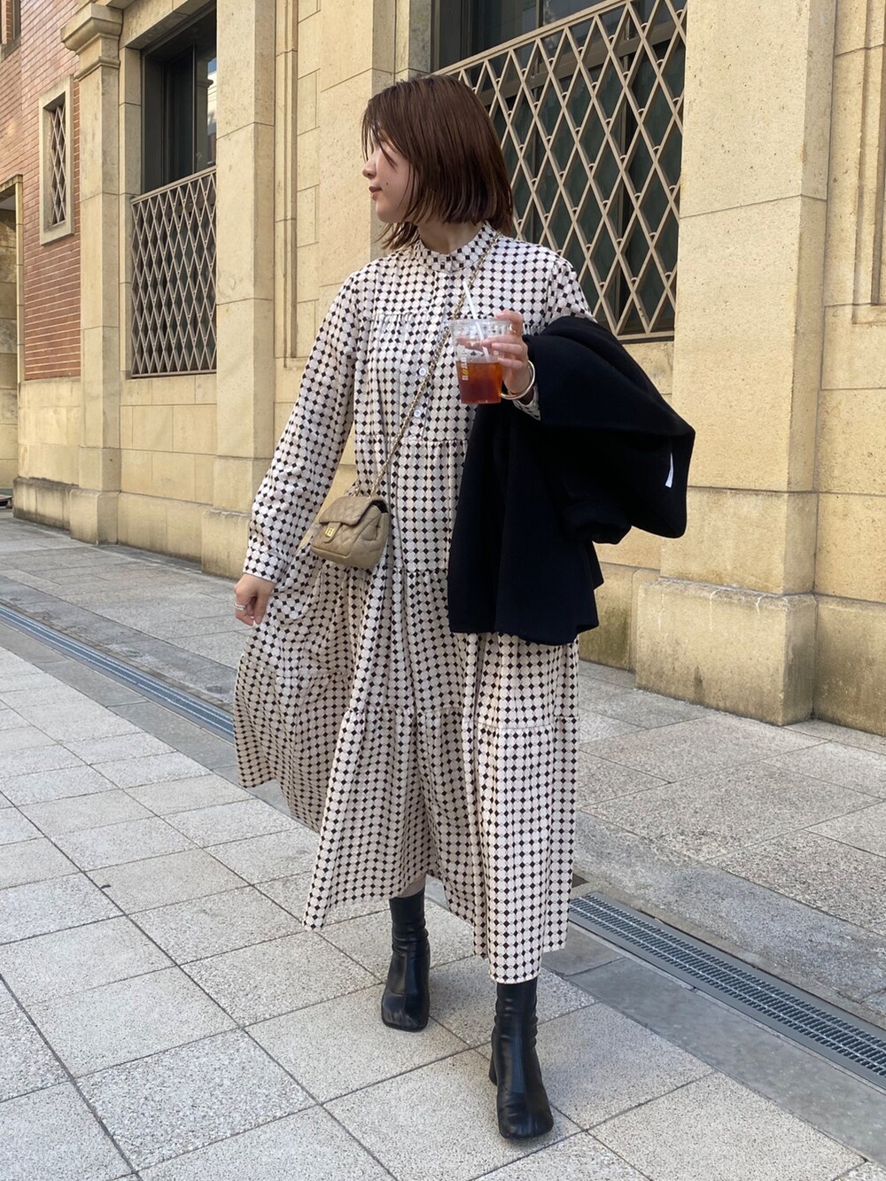 ベージュ系のワンピース、ブラック系のその他シューズ、ベージュ系のショルダーバッグを着用したレディースの冬コーディネートの3枚目の写真