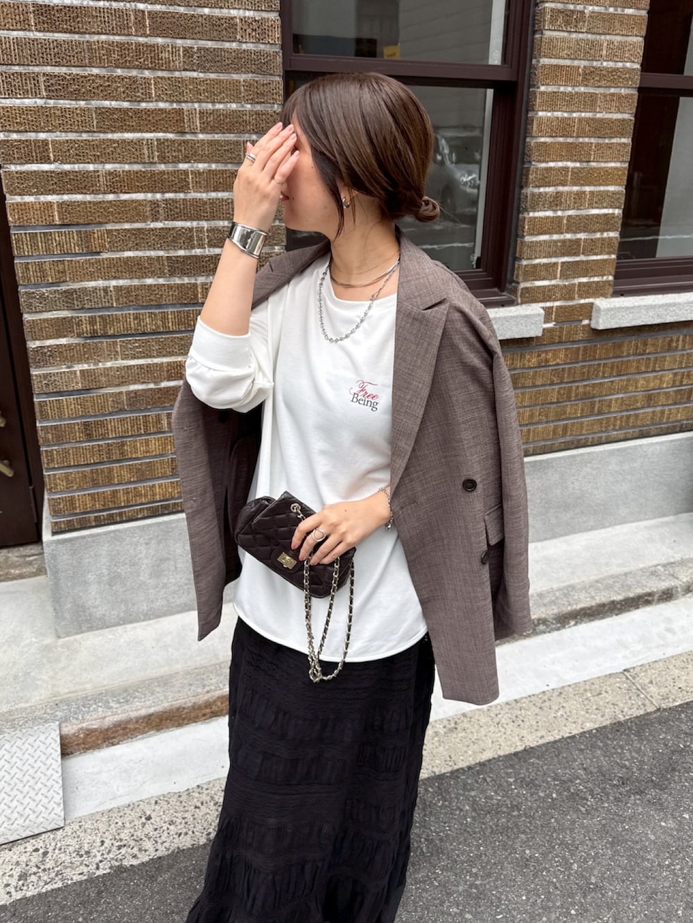 ホワイト系のTシャツ/カットソー、ブラック系のスカート、ブラウン系のテーラードジャケットを着用したレディースの冬コーディネートの2枚目の写真