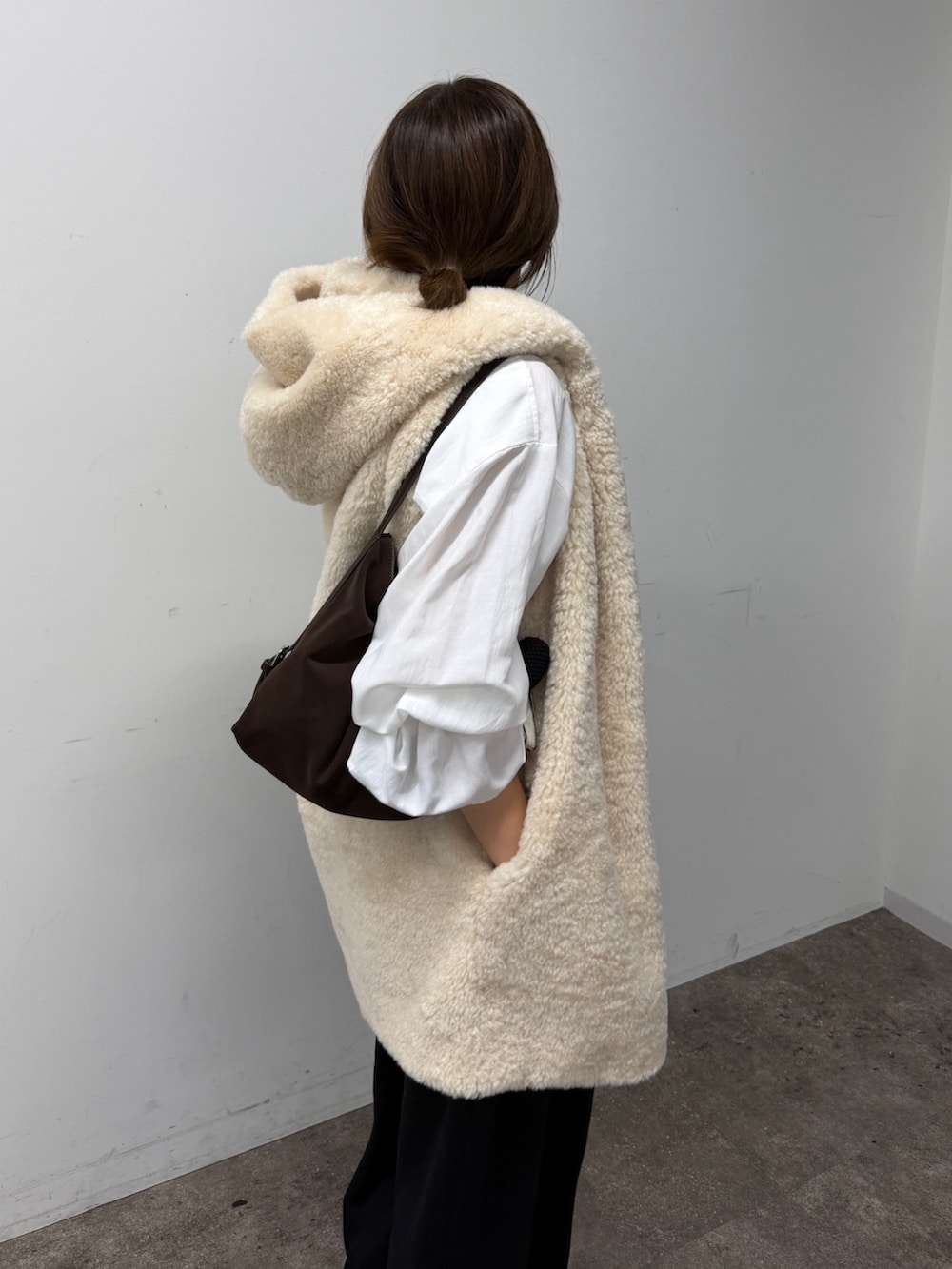 ホワイト系のシャツ/ブラウス、ホワイト系のベスト、ブラック系のスウェットパンツを着用したレディースの秋コーディネートの3枚目の写真