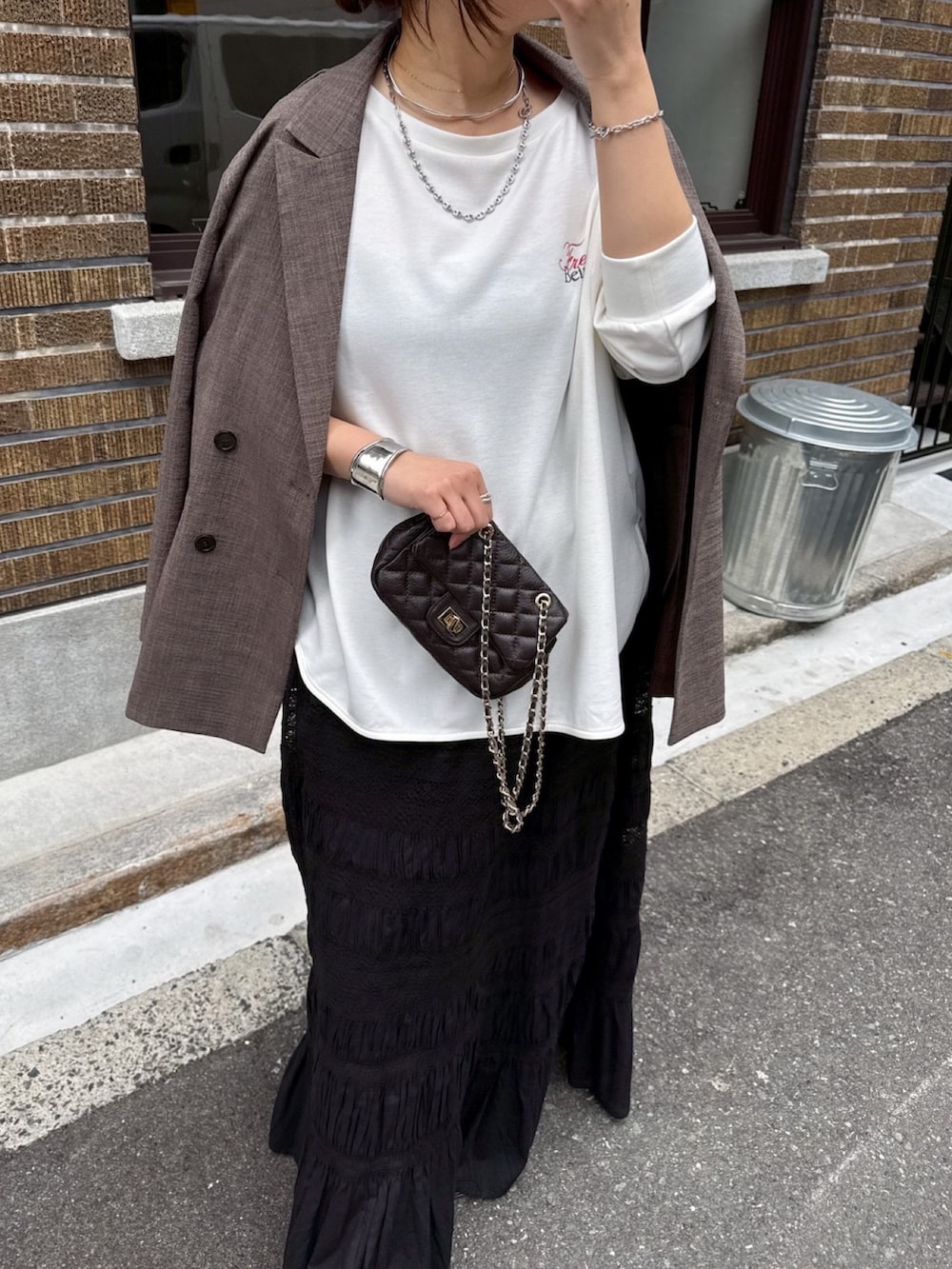 ホワイト系のTシャツ/カットソー、ブラック系のスカート、ブラウン系のテーラードジャケットを着用したレディースの冬コーディネートの3枚目の写真