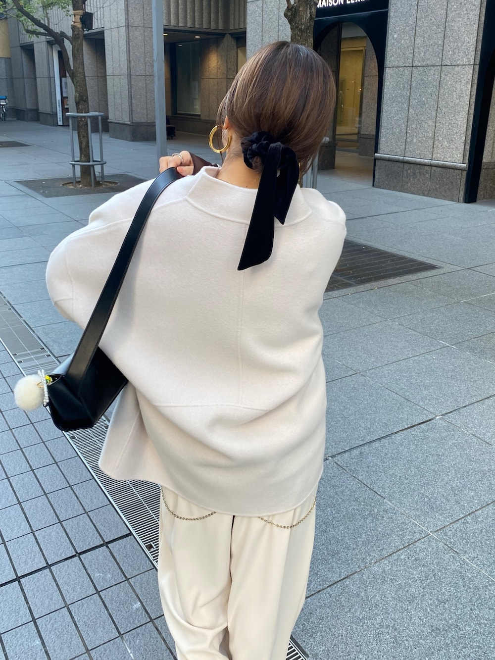 ホワイト系のその他アウター、ベージュ系のスラックス、ブラック系のショルダーバッグを着用したレディースの秋コーディネートの3枚目の写真