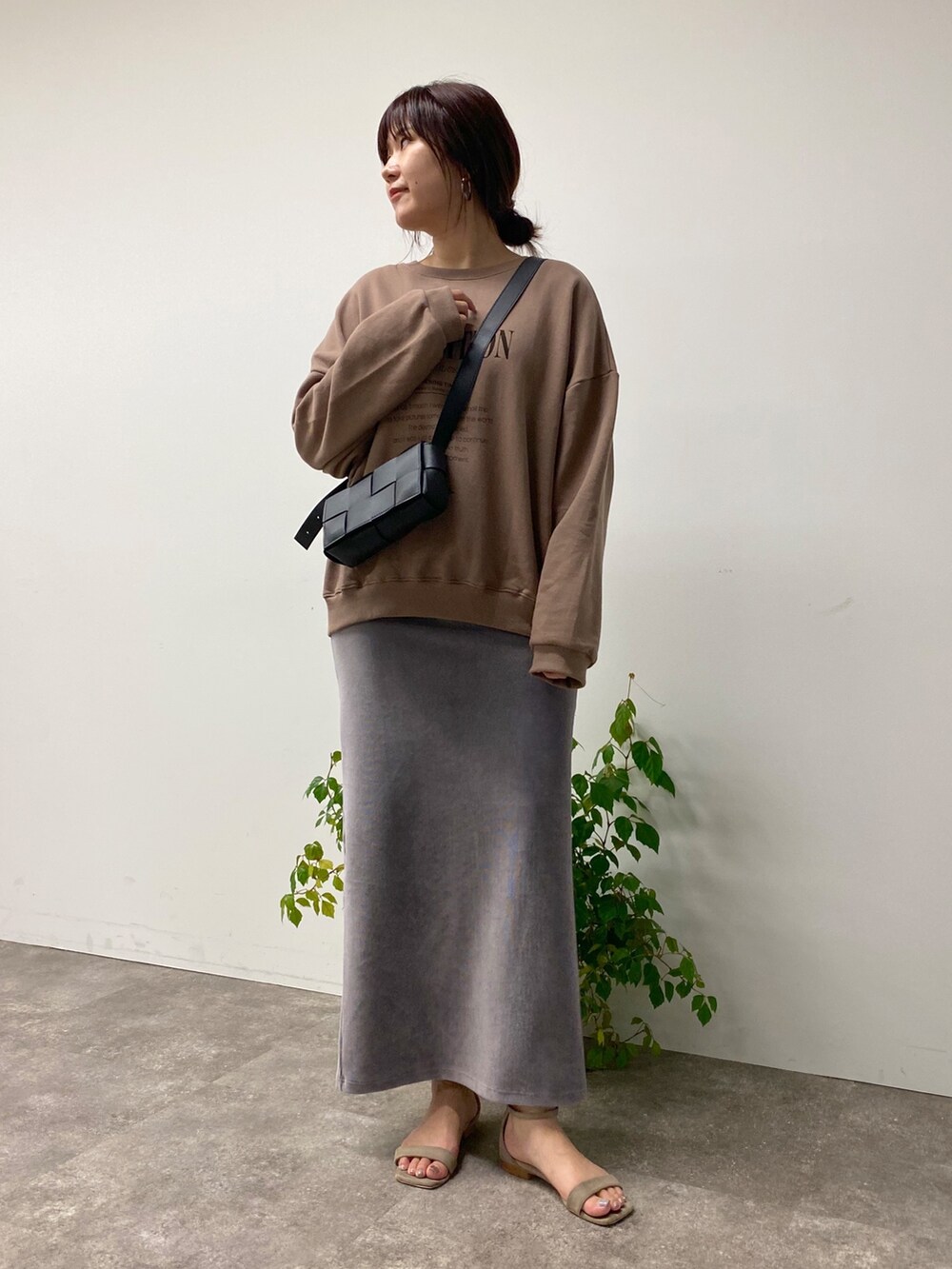 グレー系のスカート、ブラウン系のスウェット、ブラック系のバッグを着用したレディースの夏コーディネートの5枚目の写真