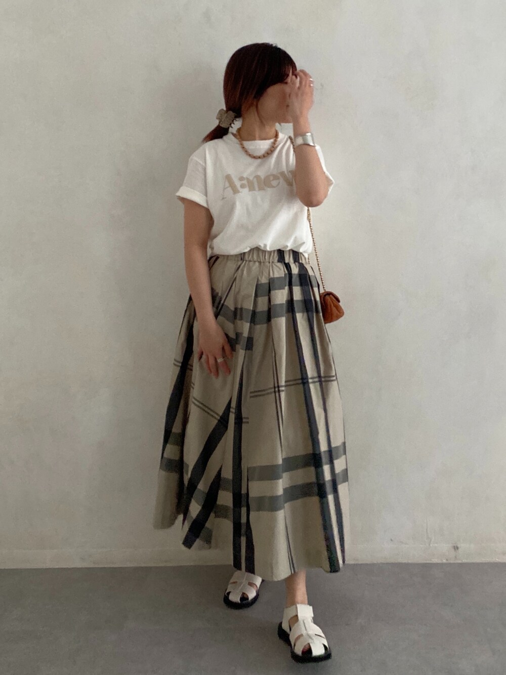ブラック系のサンダル、ホワイト系のTシャツ/カットソー、ベージュ系のスカートを着用したレディースの夏コーディネートの3枚目の写真