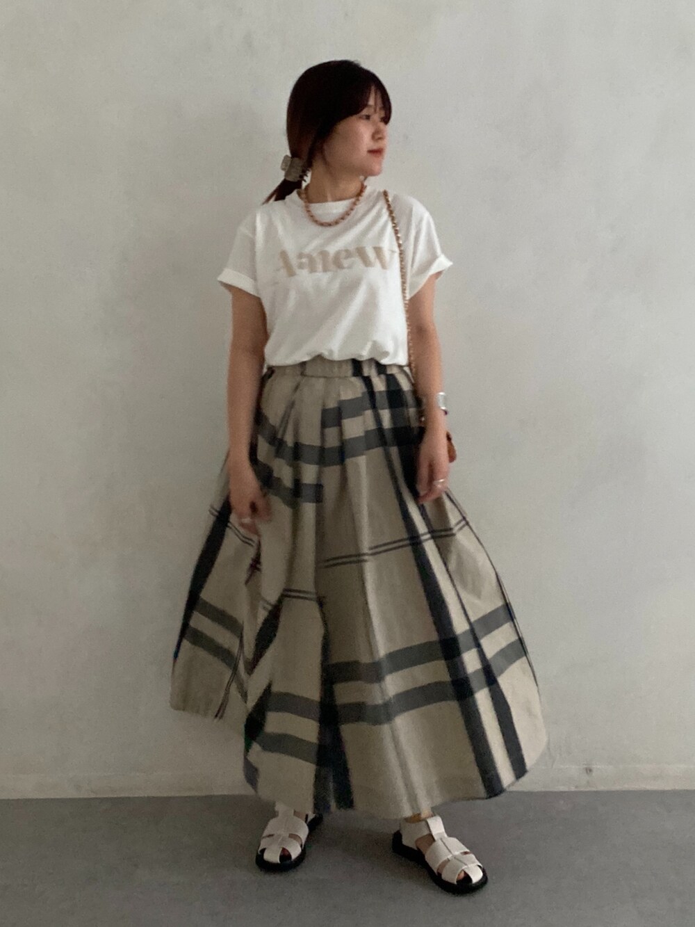 ブラック系のサンダル、ホワイト系のTシャツ/カットソー、ベージュ系のスカートを着用したレディースの夏コーディネートの4枚目の写真