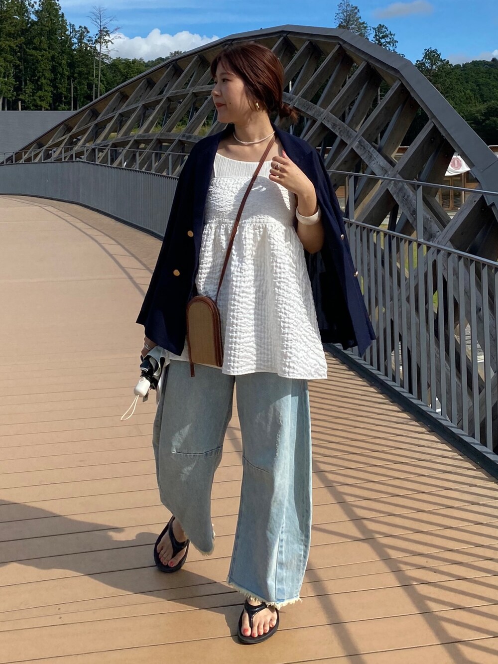 ブルー系のテーラードジャケット、ホワイト系のキャミソール、ブルー系のデニムパンツを着用したレディースの夏コーディネートの3枚目の写真
