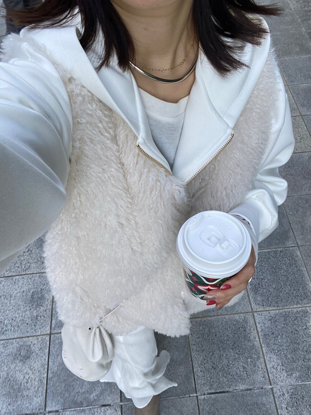 ホワイト系のベスト、ホワイト系のパーカー、ホワイト系のスカートを着用したレディースの冬コーディネートの4枚目の写真