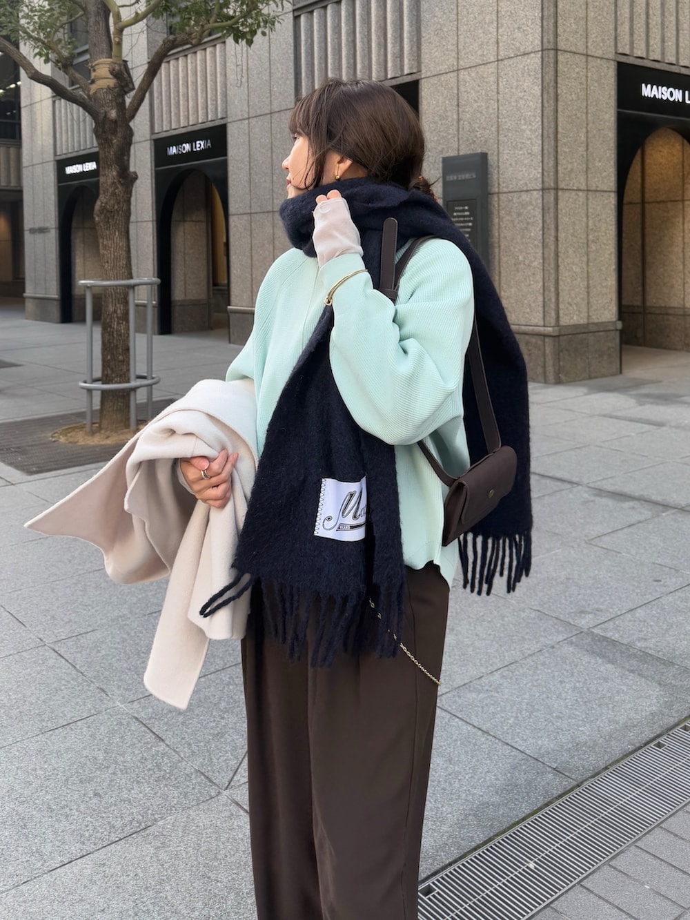 グリーン系のニット/セーター、ブラウン系のスラックス、グレー系のTシャツ/カットソーを着用したレディースの冬コーディネートの3枚目の写真