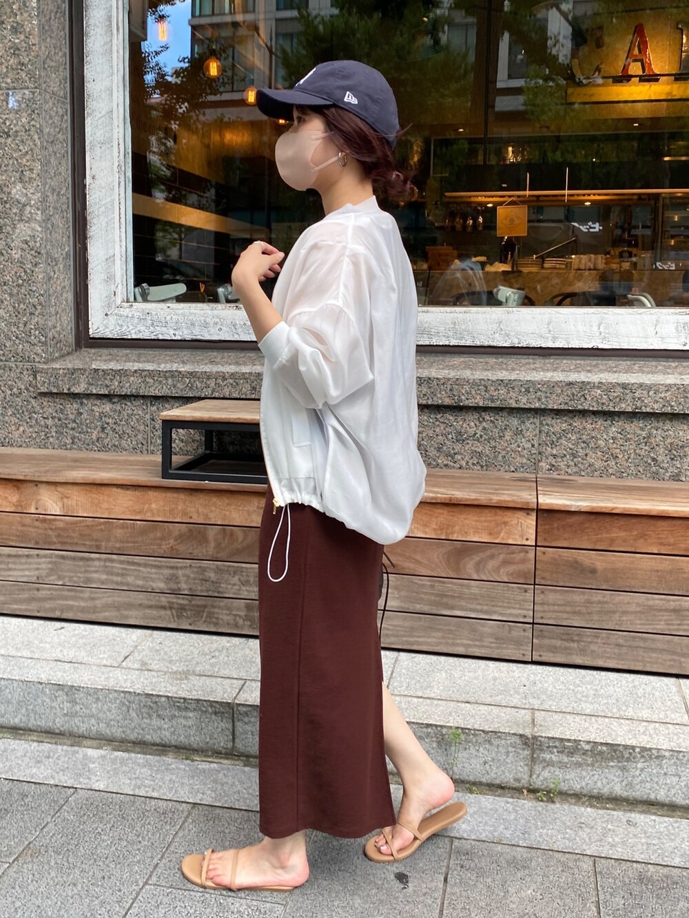 ホワイト系のブルゾン、ブラウン系のワンピース、ブルー系のキャップを着用したレディースの夏コーディネートの3枚目の写真