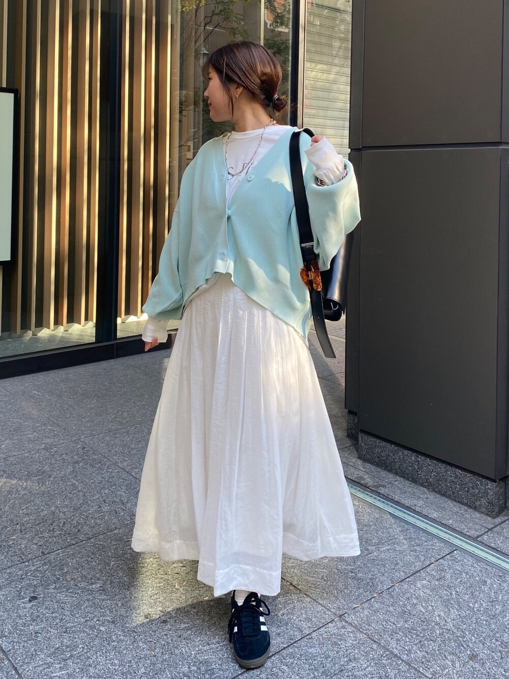 グリーン系のカーディガン/ボレロ、ホワイト系のスカートを着用したレディースの冬コーディネートの7枚目の写真