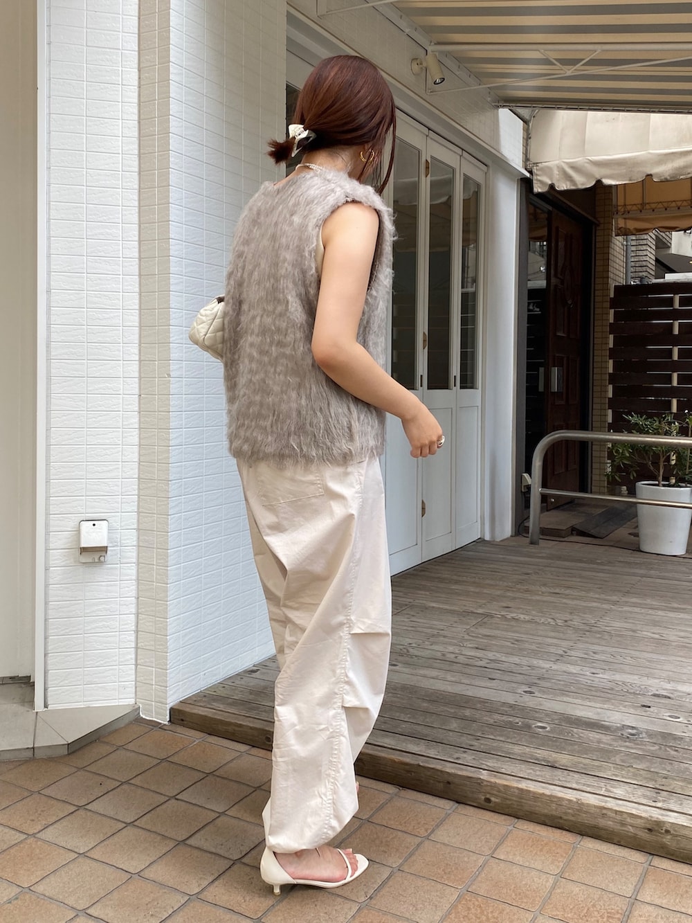 ベージュ系のベスト、ベージュ系のその他パンツ、ホワイト系のタンクトップを着用したレディースの秋コーディネートの7枚目の写真