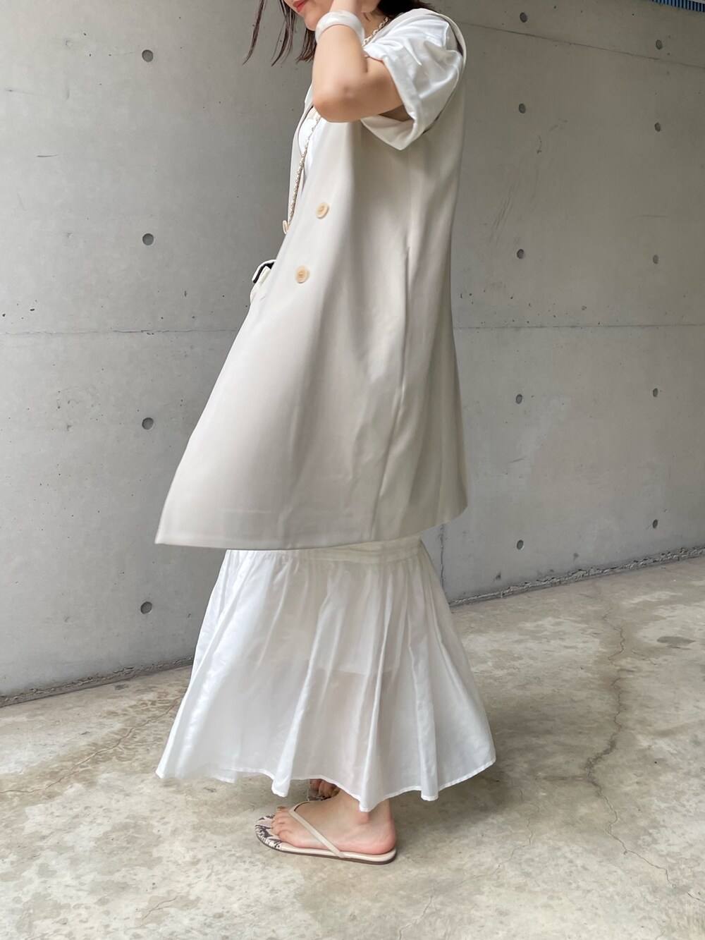 ホワイト系のスカート、ベージュ系のベスト、ホワイト系のショルダーバッグを着用したレディースの夏コーディネートの2枚目の写真