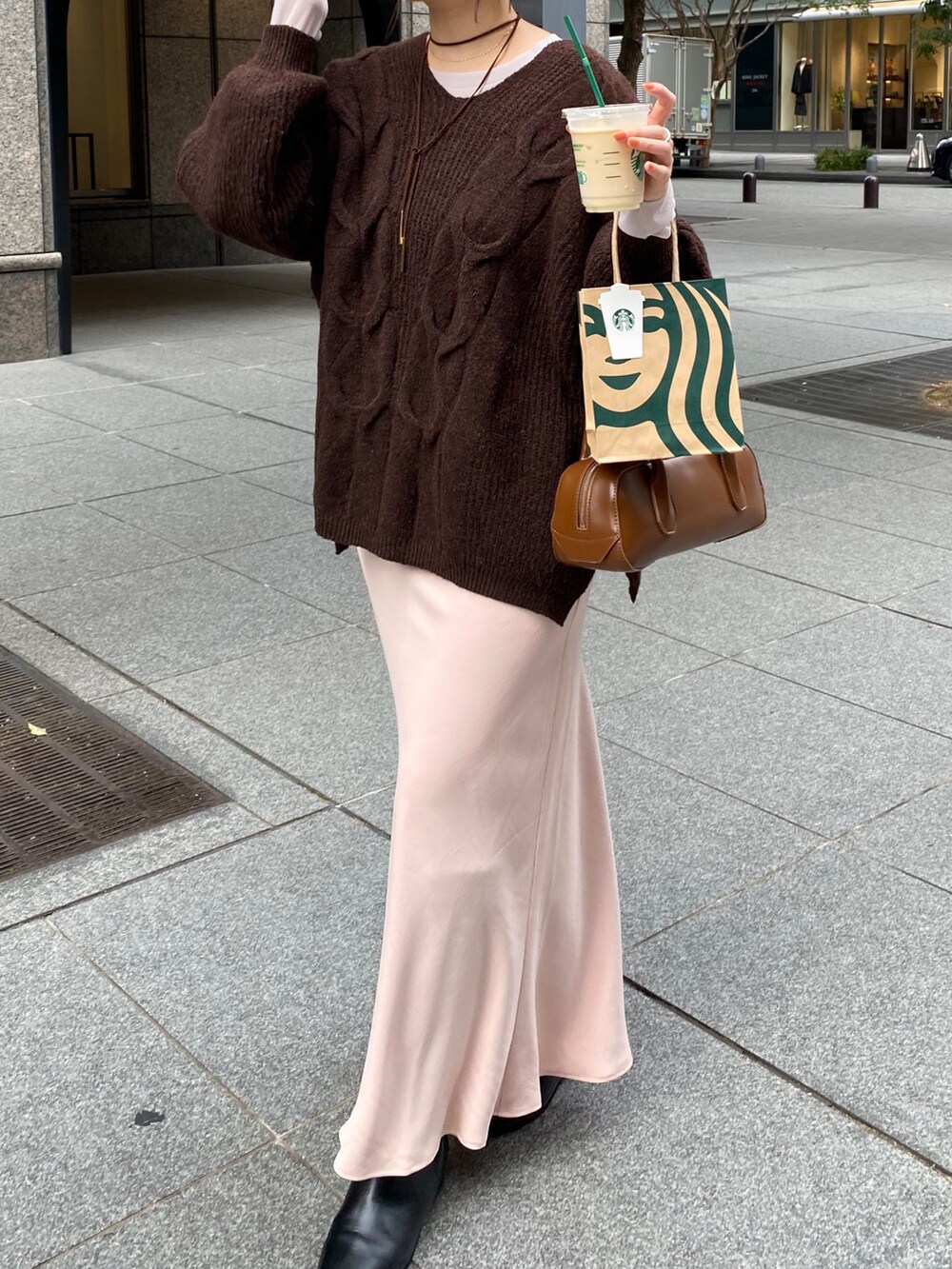 ブラウン系のニット/セーター、ピンク系のスカート、ブラック系のブーツを着用したレディースの冬コーディネートの6枚目の写真