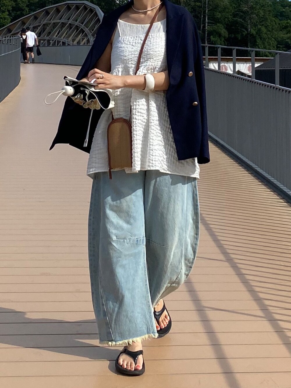 ブルー系のテーラードジャケット、ホワイト系のキャミソール、ブルー系のデニムパンツを着用したレディースの夏コーディネートの9枚目の写真