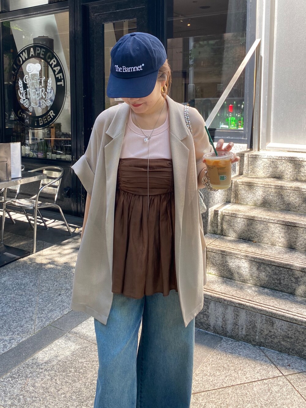 ベージュ系のテーラードジャケット、ブラウン系のキャミソール、ブルー系のデニムパンツを着用したレディースの夏コーディネートの6枚目の写真