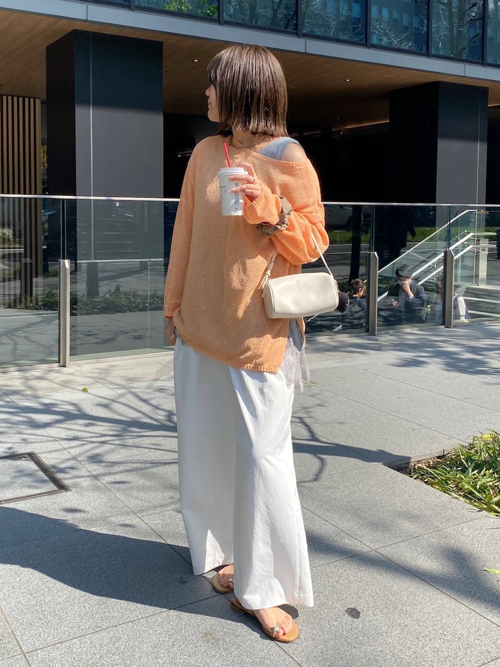 オレンジ系のニット/セーター、グレー系のTシャツ/カットソー、ホワイト系のその他パンツを着用したレディースの春コーディネートの7枚目の写真