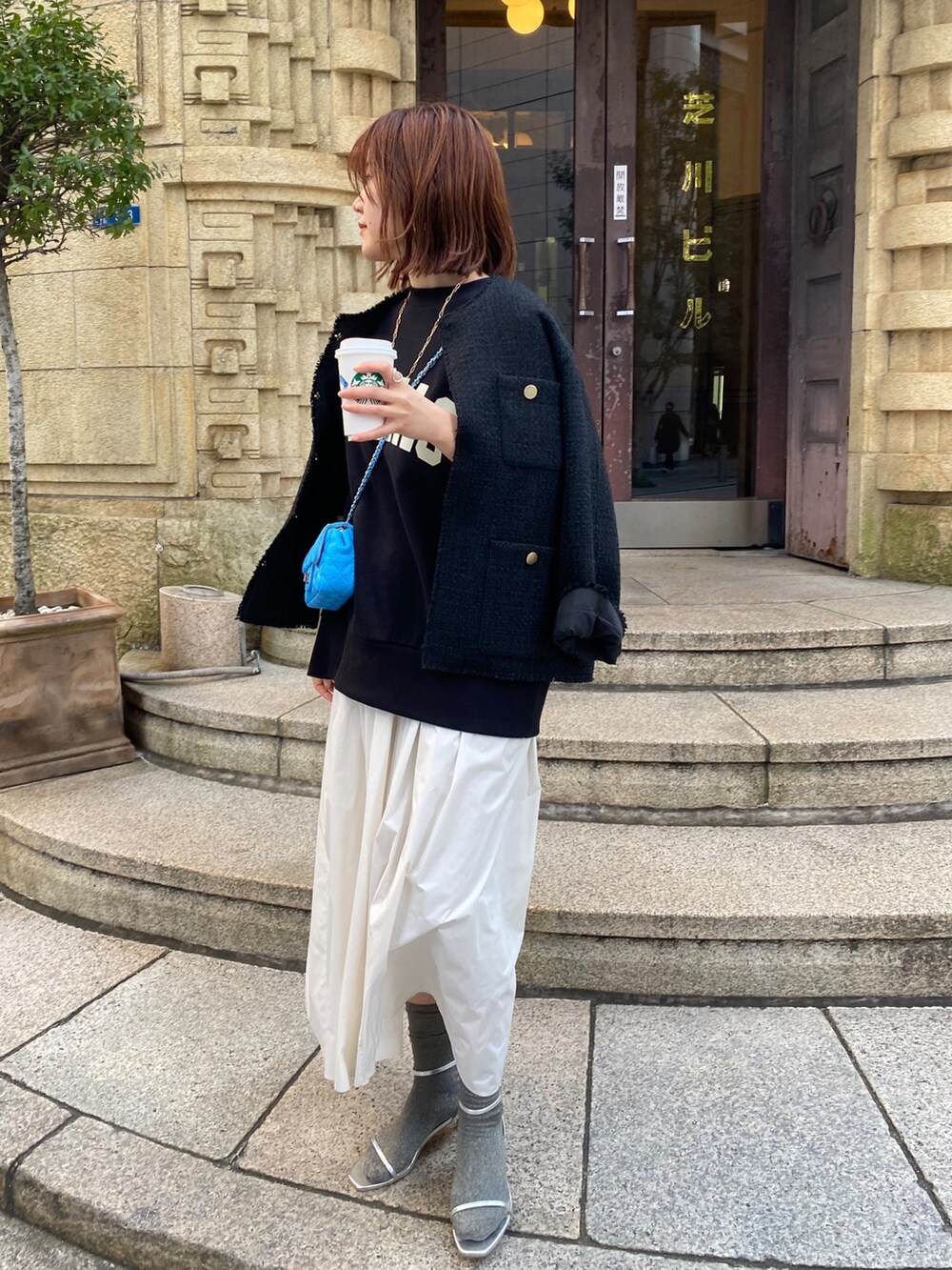 ブラック系のスウェット、ブラック系のノーカラージャケット、ホワイト系のスカートを着用したレディースの春コーディネートの2枚目の写真