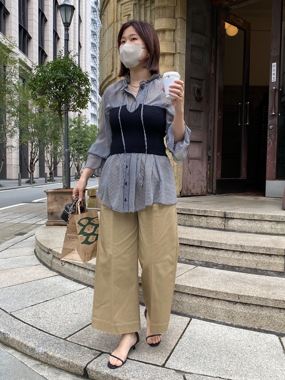 ブラック系のニット/セーター、ブラック系のシャツ/ブラウス、ベージュ系のチノパンツを着用したレディースの春コーディネートの5枚目の写真