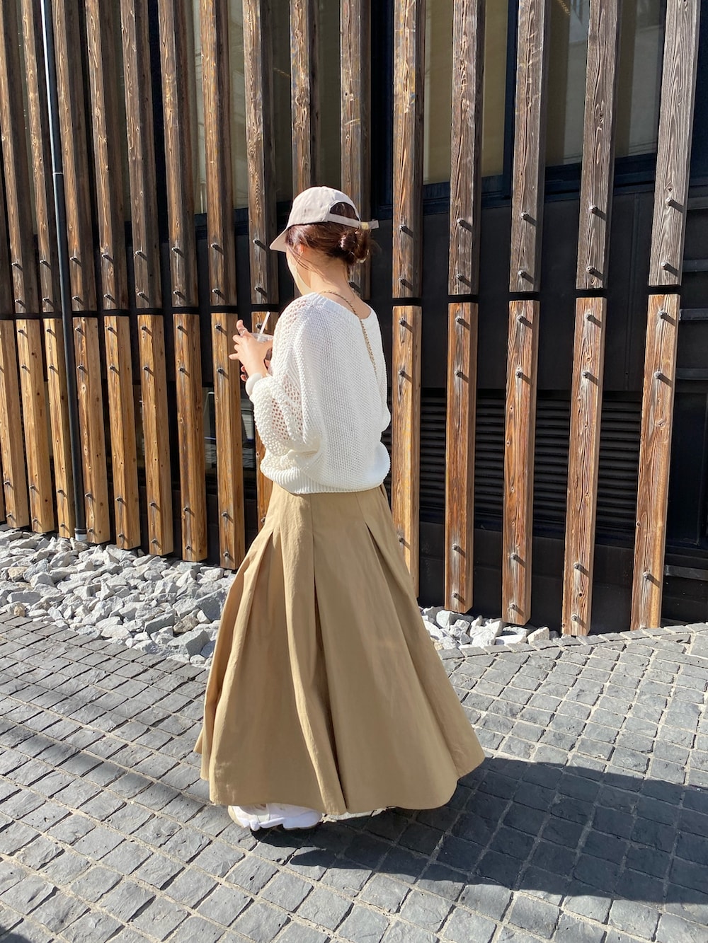 ホワイト系のニット/セーター、ベージュ系のスカート、ホワイト系のショルダーバッグを着用したレディースの春コーディネートの2枚目の写真